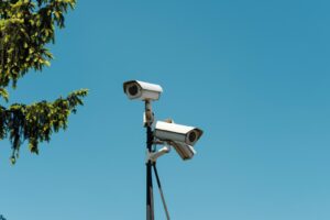 Two white security cameras mounted on a pole against a clear blue sky